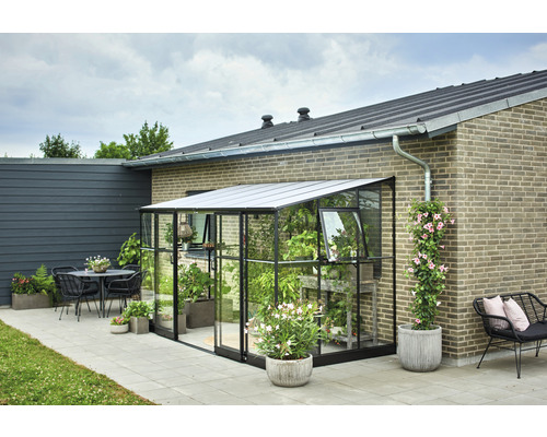 Serre en verre avec plantes à côté d''une maison et d''une terrasse