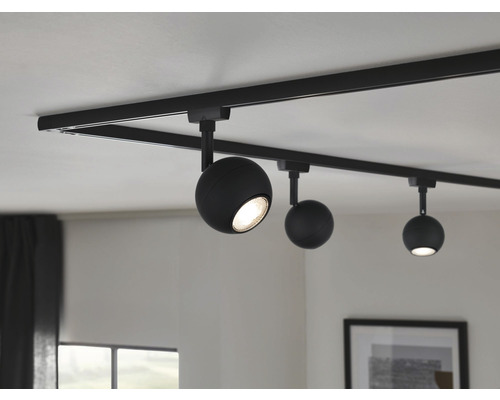 Système de rails noir avec trois spots ronds au plafond.