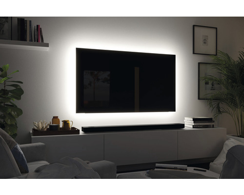 Wohnzimmer mit Fernseher, der von einer Lichtleiste umgeben ist und auf einem Lowboard steht