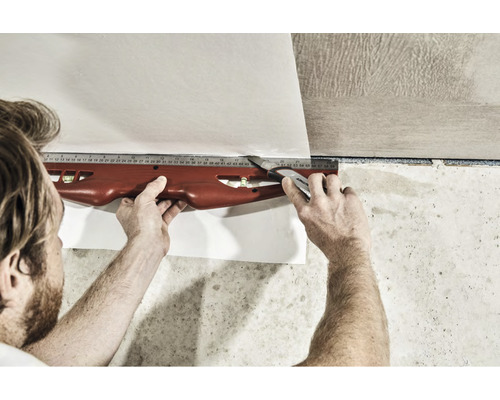 Zuschneiden einer Tapete mit Cutter und Wasserwaage