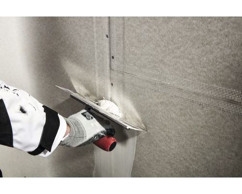 Application d''un tissu d''armature sur un mur à l''aide d''une taloche.