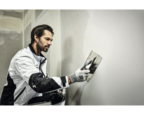 Artisan lissant un mur avec une lisseuse.