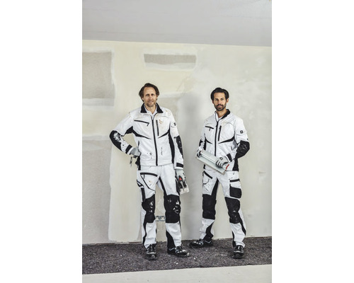 Deux artisans en vêtements de travail devant un mur enduit.