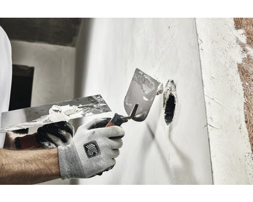 Artisan enduisant un mur avec deux spatules