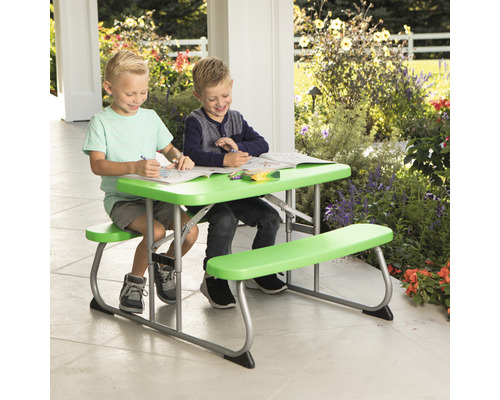 Deux enfants sont assis à une table de pique-nique verte à l''extérieur et colorient.