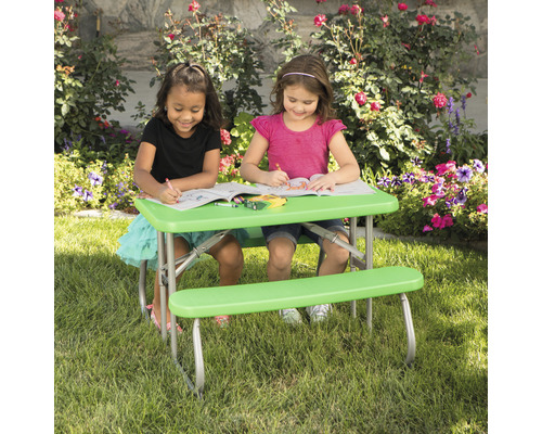 Deux enfants sont assis à une table d''enfant verte avec des bancs dans le jardin et colorient.