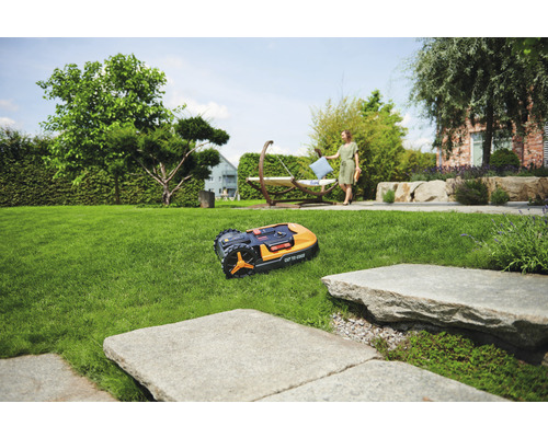 Robot tondeuse sur pelouse dans jardin avec femme et hamac