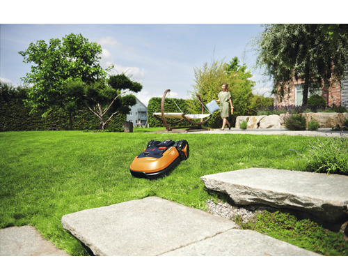 Tondeuse robot sur une pelouse dans un jardin avec des arbres et des meubles de jardin