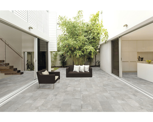 Helle Terrasse mit grauen Bodenplatten, Sitzmöbeln und Bepflanzung