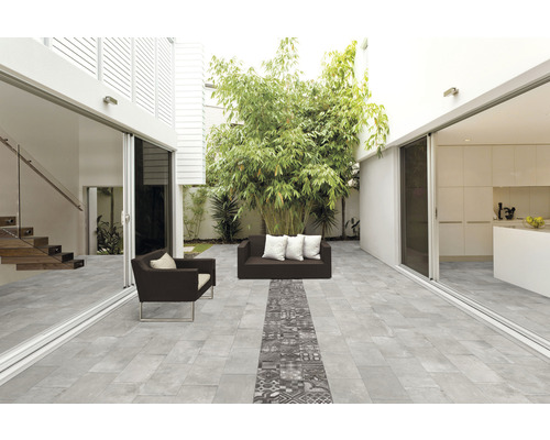 Terrasse mit grauen Bodenfliesen, Sitzmöbeln und Bepflanzung