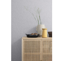 Gemusterte Tapete über einem Schrank mit Rattanfront, darauf Vasen und eine Schale