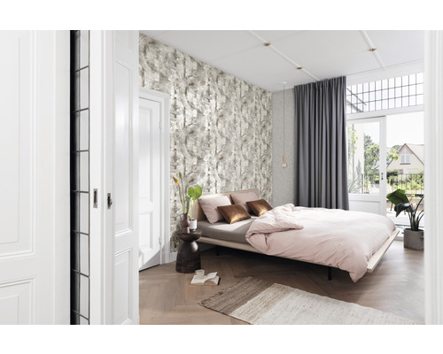 Helles Schlafzimmer mit Bett, gemusterter Tapete und geöffneter Balkontür