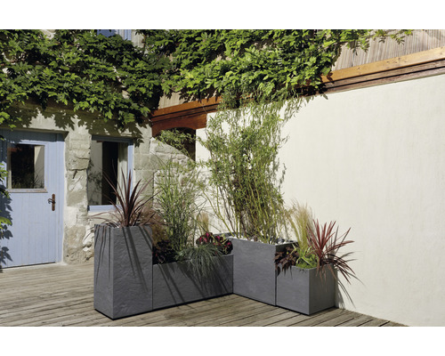 Drei graue Pflanzkästen aus Steinzeug mit Bepflanzung im Aussenbereich.