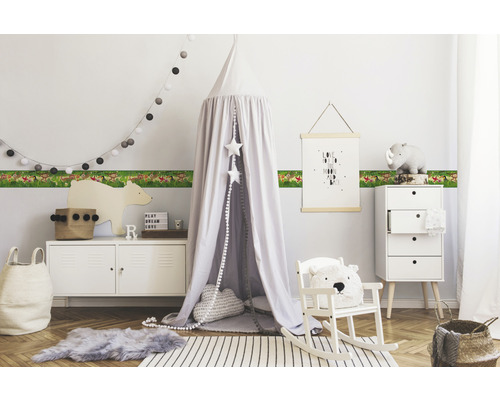 Kinderzimmer mit Tiermusterbordüre, Baldachinbett und weißen Möbeln