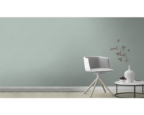 Szene mit Stuhl, Tisch und Dekorationsgegenständen vor einer Wand