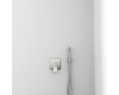 Robinet de douche et douchette à main sur un mur blanc