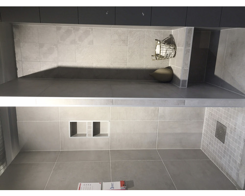 Salle de bain avec carrelage gris, étagères et espace douche