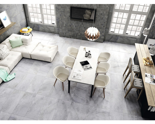 Salon lumineux avec carrelage, canapé, table à manger et chaises