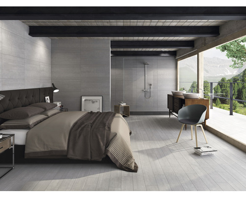 Chambre à coucher lumineuse avec salle de bains, équipée de carreaux de sol, de carreaux muraux, d''un lit et d''un lavabo.