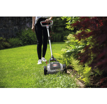 Une jardinière travaille avec un coupe-bordures dans le jardin.