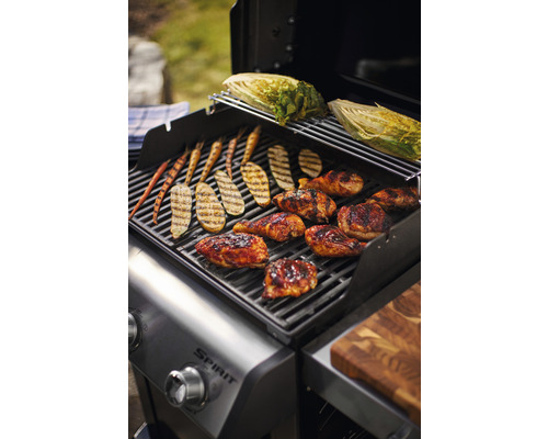 Grill mit Hähnchen, Zucchini, Karotten und Salat auf dem Rost.
