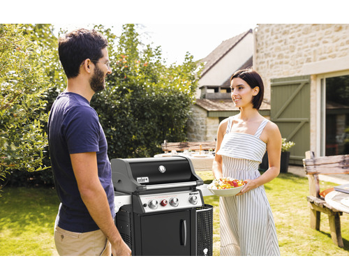 Weber Gasgrill mit zwei Personen im Garten.