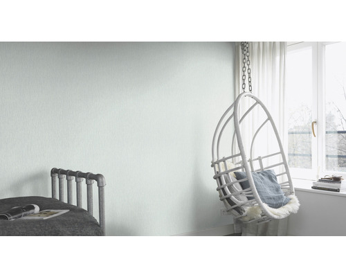 Helles Zimmer mit Bett, Hängesessel und hellgrüner Vliestapete