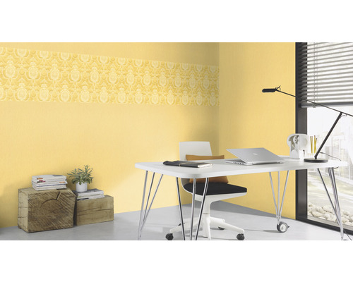 Büro mit gelber gemusterter Bordüren Tapete, Schreibtisch, Stuhl und Accessoires.
