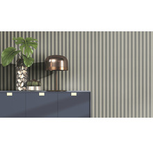 Arrangement décoratif avec lampe de table, vase, plante et cactus sur une armoire devant un papier peint rayé.