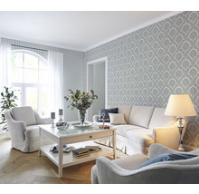 Salon avec canapé, fauteuils, table basse et papier peint à motifs pour une ambiance élégante