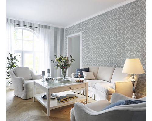 Salon avec canapé, fauteuils, table basse et papier peint à motifs pour une ambiance élégante