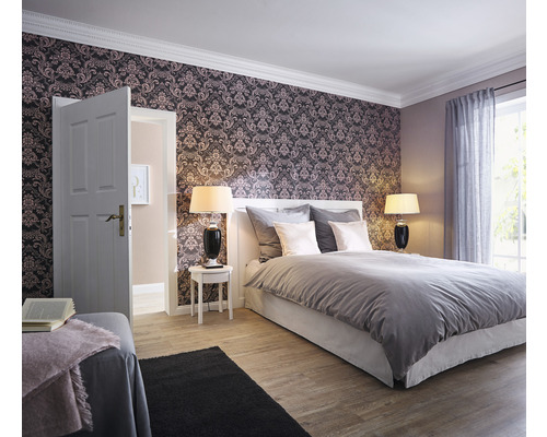 Schlafzimmer mit gemusterter Tapete, Bett, Nachttischen und Lampen.