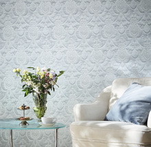 Dekoratives Wohnzimmer mit gemusterter Tapete, Sessel und Blumenstrauß