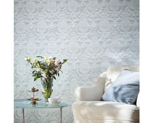 Dekoratives Wohnzimmer mit gemusterter Tapete, Sessel und Blumenstrauß