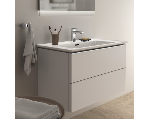 Meuble sous-vasque avec deux tiroirs, robinetterie et miroir dans une salle de bains lumineuse.