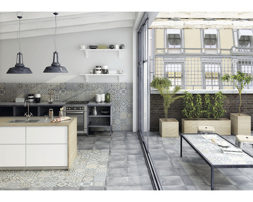 Cuisine claire avec îlot de cuisson, carrelage et accès au balcon avec des plantes