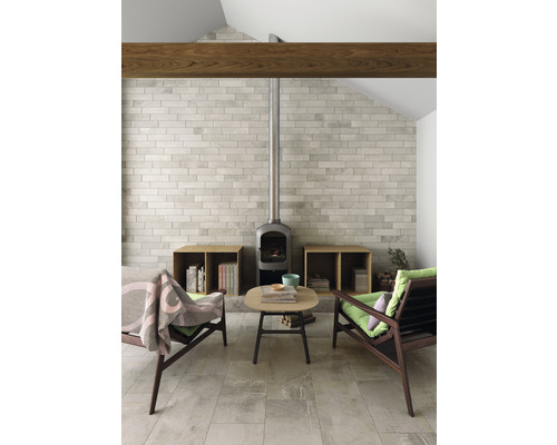 Salon avec poêle à bois, sol carrelé, deux fauteuils et petite table