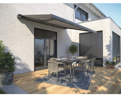 Terrasse avec store, table et chaises contre une maison