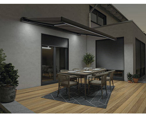 Terrasse avec store, table et chaises devant une maison