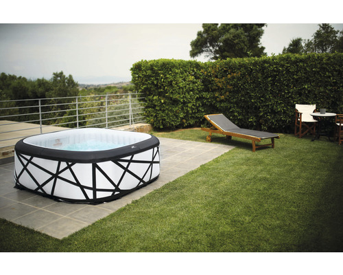 Aufblasbarer Whirlpool auf einer Terrasse mit Liegestuhl und Gartenmöbeln im Hintergrund.