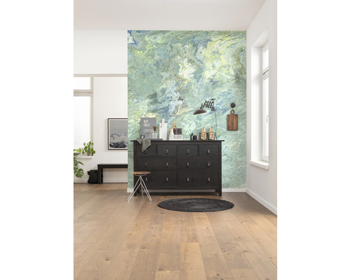 Helles Zimmer mit gemusterter Wand, dunkler Kommode und Holzboden