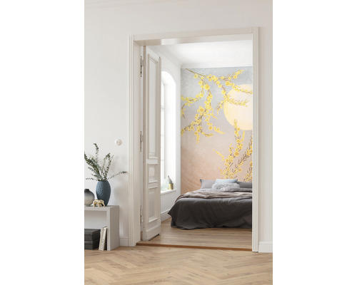 Ein Schlafzimmer mit einer Wandtapete mit gelben Blütenmustern ist durch eine offene Tür sichtbar.