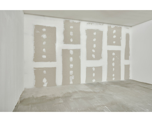 Pièce non finie avec murs en plaques de plâtre et sol en béton.