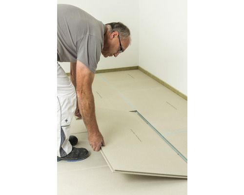 Artisan posant des éléments de chape sèche dans une pièce