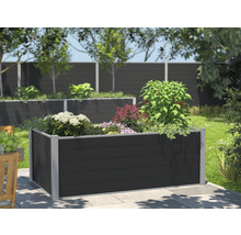 Jardinière surélevée en plastique avec diverses plantes dans un jardin.