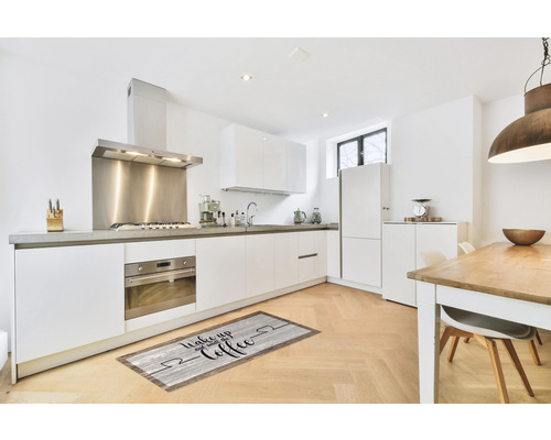 Cuisine moderne avec armoires blanches et un tapis de sol avec un motif de café