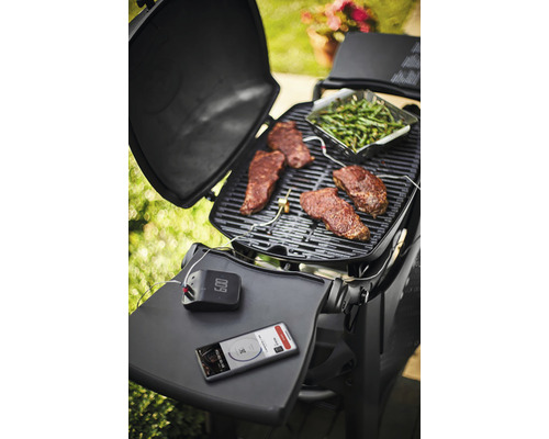 Scène de grillades avec steaks, légumes verts, thermomètre de grill et smartphone sur un grill