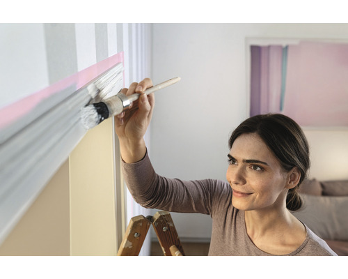 Femme peignant un mur avec un pinceau et de la peinture.