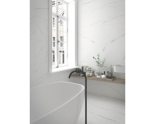 Salle de bains lumineuse avec carrelage imitation marbre, baignoire et fenêtre