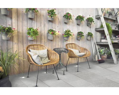 Aménagement de terrasse avec fauteuils en rotin, petite table d''appoint et décoration murale avec pots de fleurs.